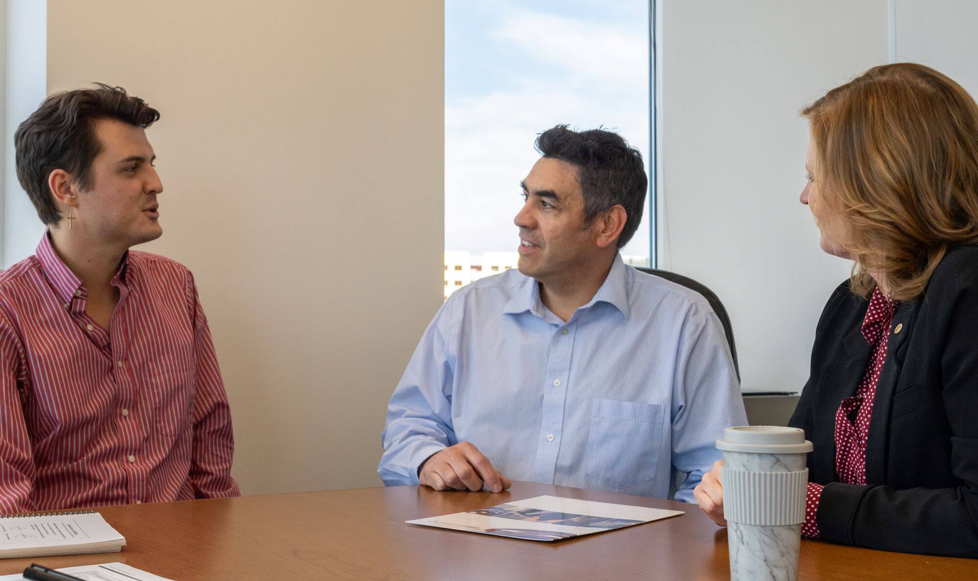 Three professionals in a meeting discussing advisory and development strategies.