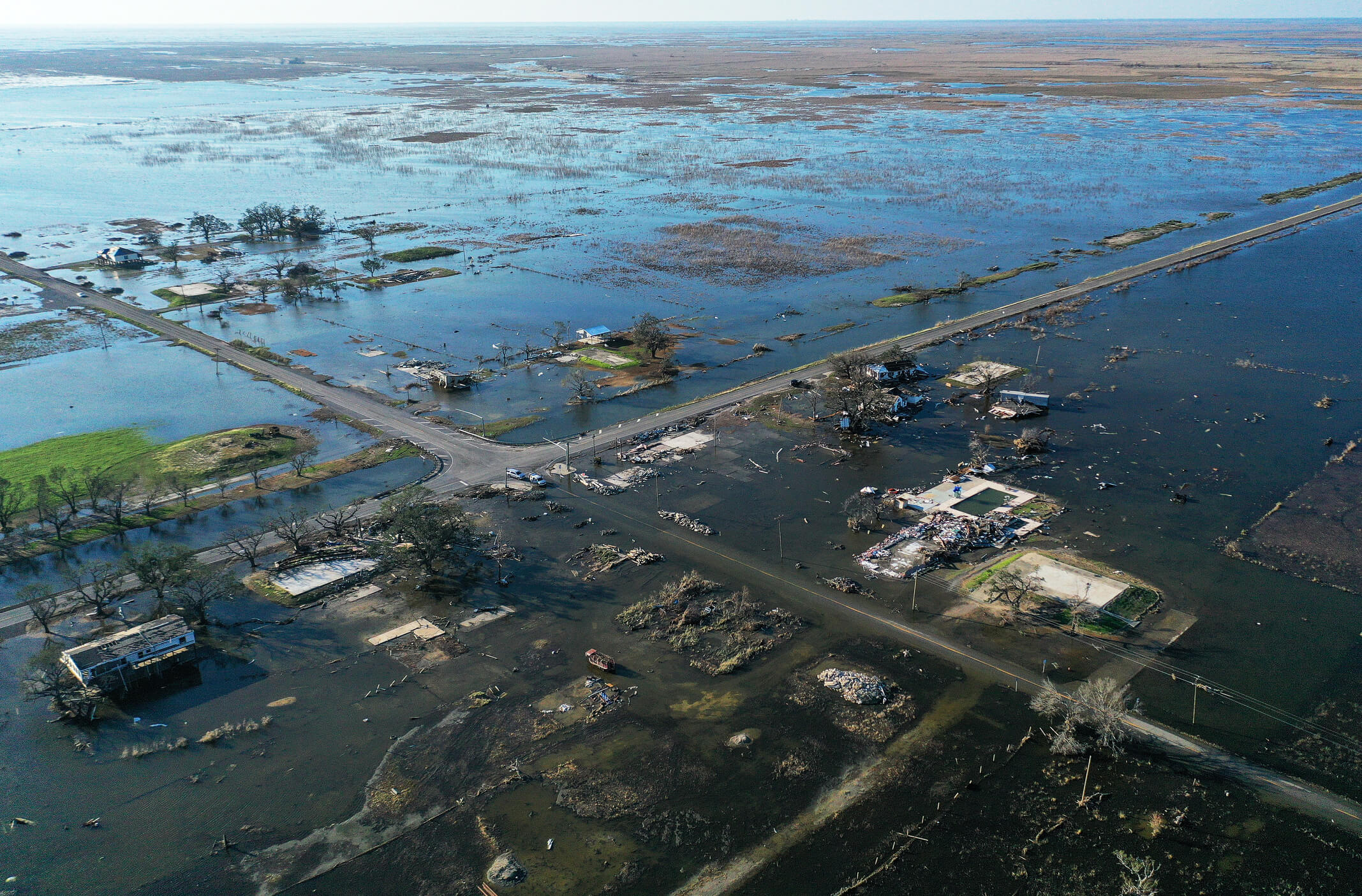 Drone view of coastal flooding and widespread hurricane damage affecting roads, buildings, and infrastructure.