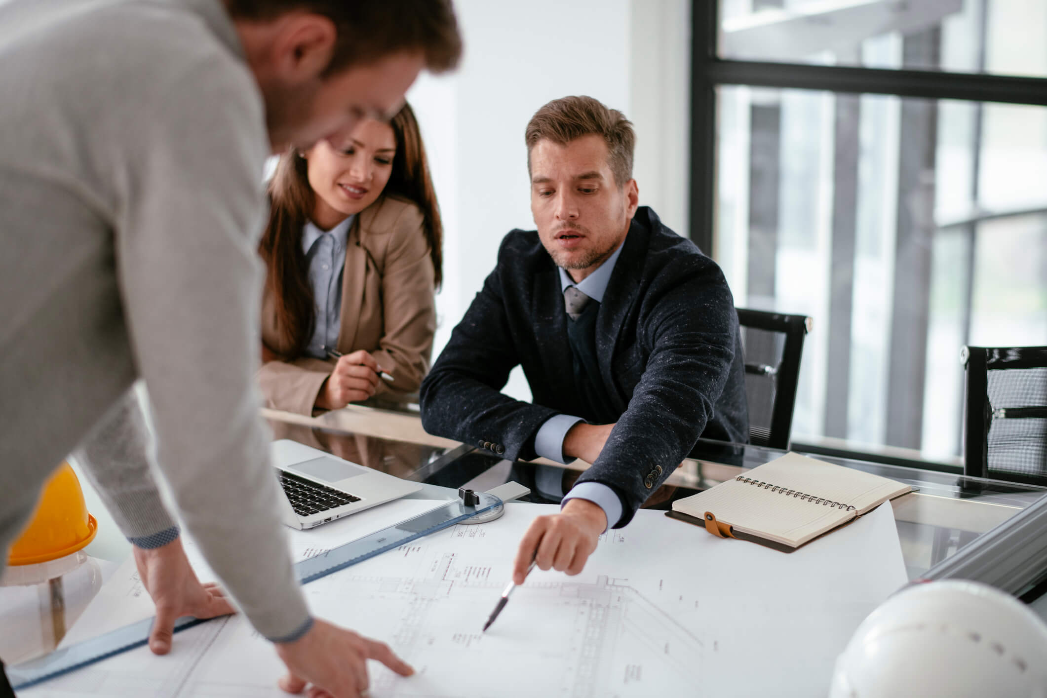 Two men and a woman reviewing business plans at a conference table