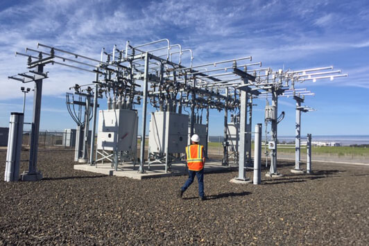 Engineer walking through and inspecting equipment at an outdoor electrical power substation