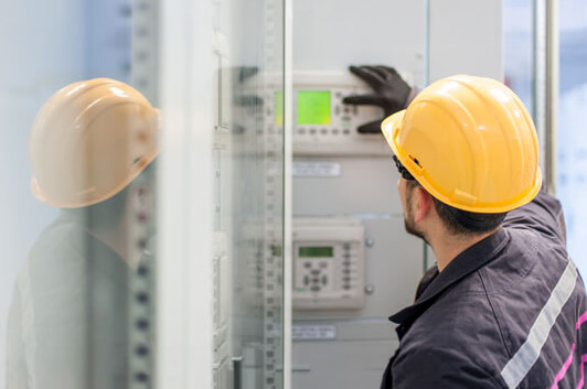 Technician wearing a hard hat examining controls