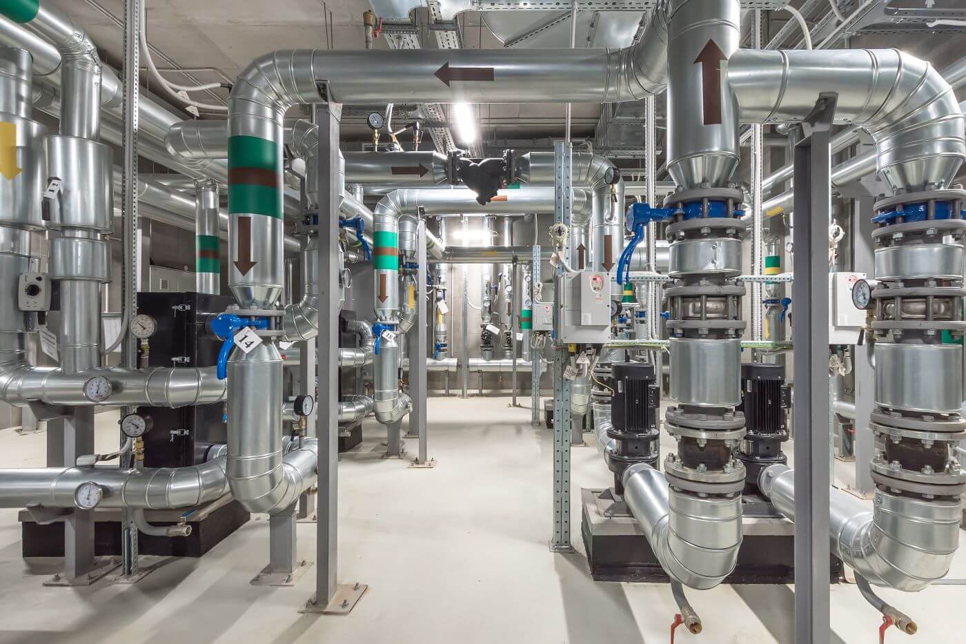 "Interior of an industrial facility showing a complex network of stainless steel pipes, valves, and mechanical equipment used for fluid distribution and control.