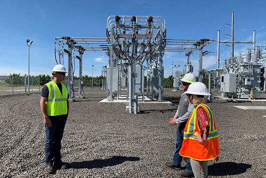 Engineers discussing equipment while standing inside an electrical power substation