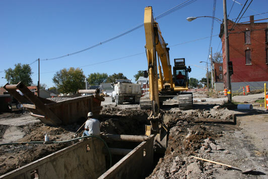 Excavator digging a trench for underground utility installation during street construction