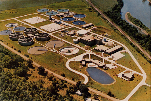 Aerial view of a wastewater treatment plant with clarifiers, basins, and treatment buildings