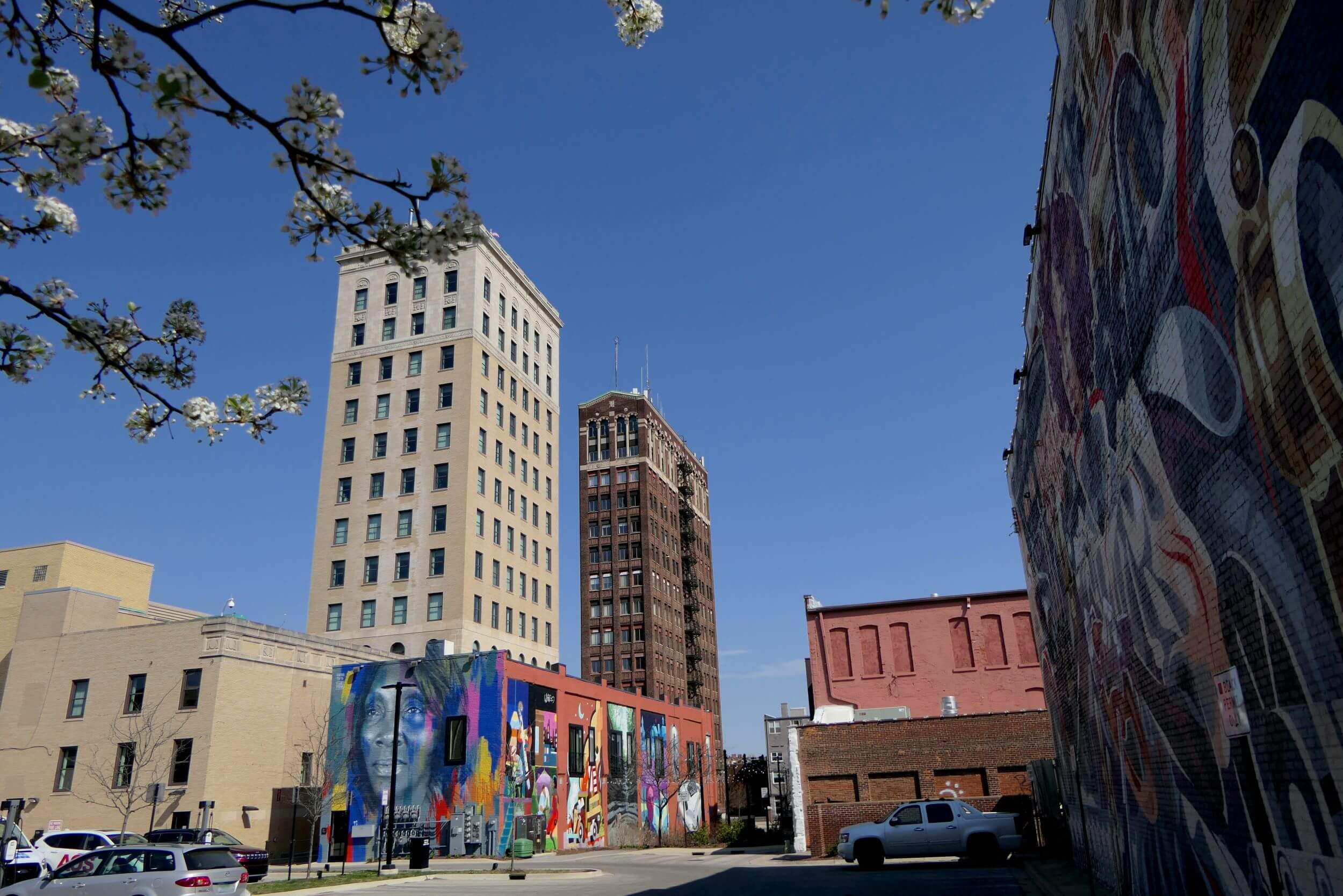 Street view of downtown Jackson, Michigan, featuring historic buildings, colorful murals, and a clear blue sky.